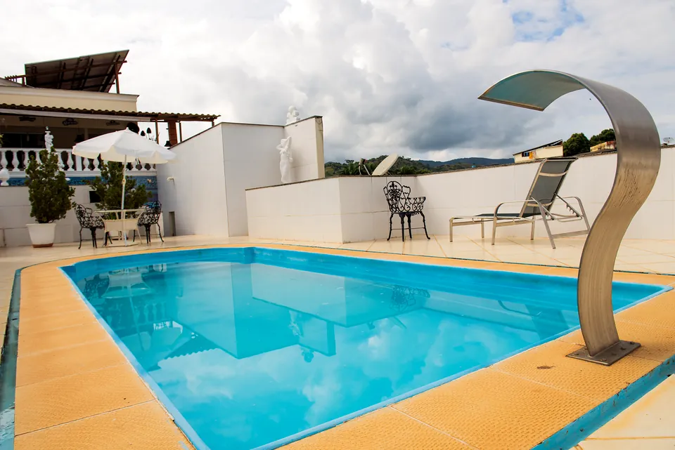 Piscina com cascata de inox, espreguiçadeiras e vista para os morros de Ipanema